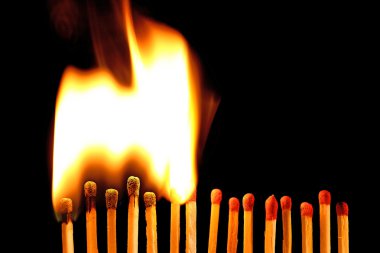 Line of lighted matches on black background clipart