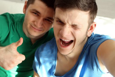 Kanepede oturan ve üstünde hareket eden telefon fotoğraf yapma iki yakışıklı genç adam