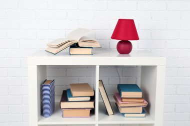 Kitap ve tuğla duvar arka lamba ile ahşap raf