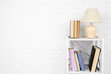 Kitap ve tuğla duvar arka lamba ile ahşap raf