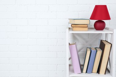 Kitap ve tuğla duvar arka lamba ile ahşap raf