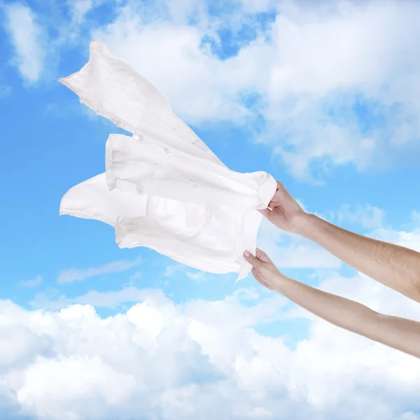 Hands holding flying shirt on sky background — Stock Photo, Image