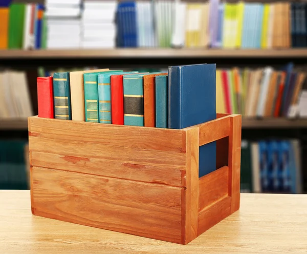 Books in wooden crate on bookshelves background — Stock Photo, Image