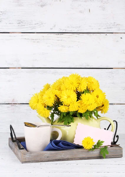 Yellow flowers in decorative teapot on wooden background — Stock Photo, Image