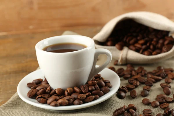 Tazza di caffè con fagioli su sfondo rustico in legno — Foto Stock