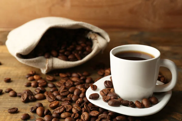 Taza de café con frijoles sobre fondo rústico de madera —  Fotos de Stock