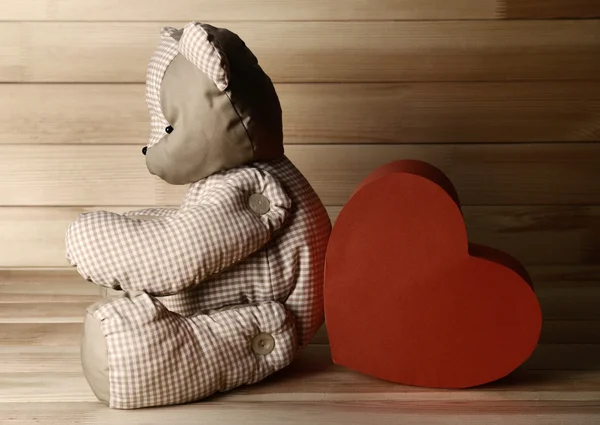 Oso de peluche con corazón rojo sobre fondo de madera — Foto de Stock