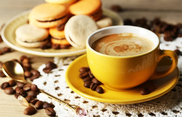 Macarrones coloridos suaves y café en taza sobre fondo de mesa de madera —  Fotos de Stock