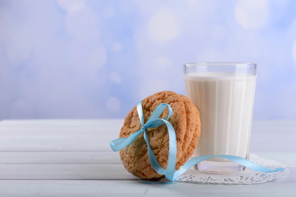 Chutné cookies a sklenici mléka na dřevěné tabulce barev, na světlé pozadí — Stock fotografie