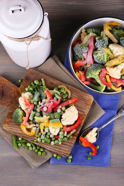 Frozen vegetables on cutting board, on napkin, on wooden table background — Stock Photo, Image