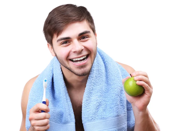Πορτρέτο της χαμογελαστός νεαρός με οδοντόβουρτσα και πράσινο μήλο που απομονώνονται σε λευκό — Φωτογραφία Αρχείου