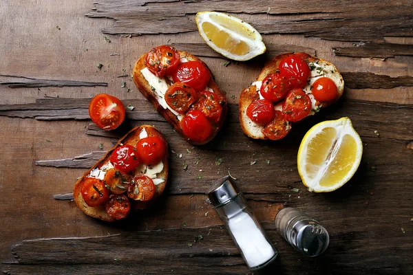 Plátky bílé toastový chléb s konzervovaných rajčat a vápna na dřevěný stůl pozadí — Stock fotografie