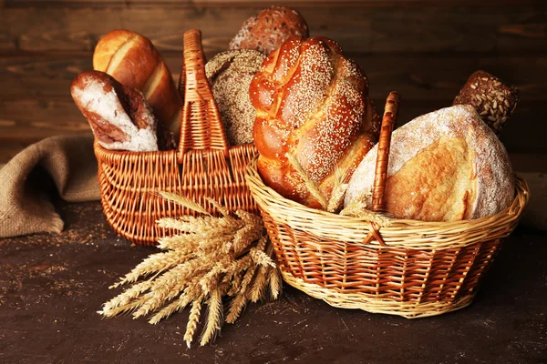 Pane diverso con orecchie in cesto su sfondo di legno — Foto Stock