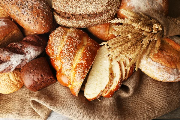Different bread with ears on sackcloth background — Stock Photo, Image