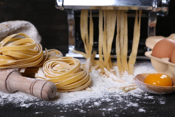 Teigwarenmaschine aus Metall und Zutaten für Pasta auf Holzgrund — Stockfoto