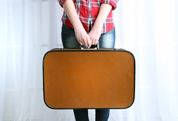 Mujer sosteniendo maleta vieja sobre fondo de tela — Foto de Stock
