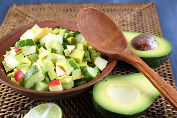 Insalata con mela e avocado in ciotola su vimini stand close up — Foto Stock