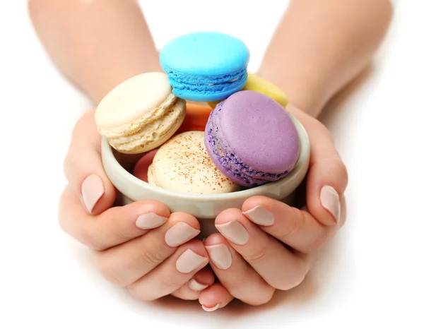 Bowl of tasty colorful macaroons in female hands isolated on white — Stock Photo, Image