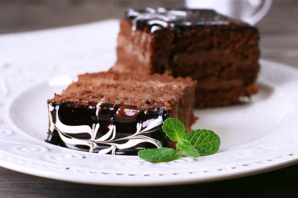 Leckere Stücke Schokoladenkuchen mit Minze auf Holztischhintergrund — Stockfoto