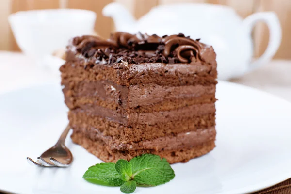 Sabroso pedazo de pastel de chocolate con menta y canela en la mesa de madera y tablones borrosa fondo, vista de cerca — Foto de Stock