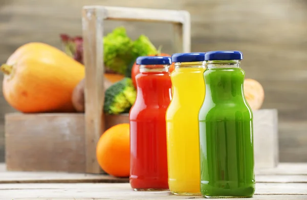 Glazen flessen van verse gezonde SAP met set van groenten en fruit op houten achtergrond — Stockfoto