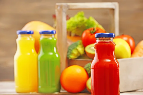 Glazen flessen van verse gezonde SAP met set van groenten en fruit op houten achtergrond — Stockfoto