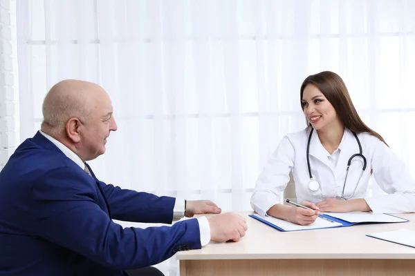 Young female doctor receiving patient in her office — Stock Photo, Image