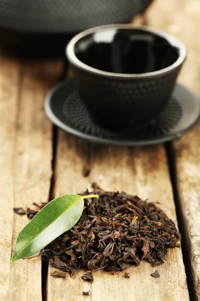 Black tea with leaf on old wooden table — Stock Photo, Image