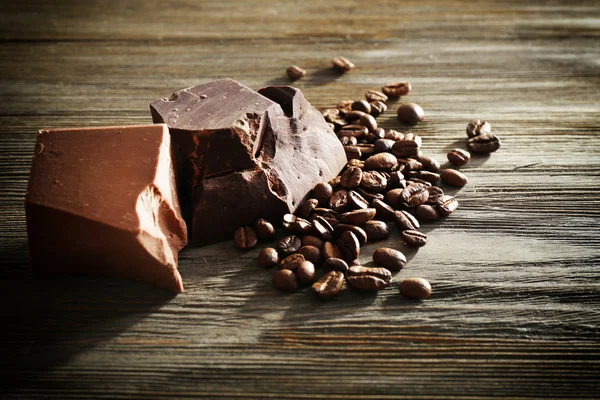 Barras de chocolate con granos de café sobre fondo de madera —  Fotos de Stock