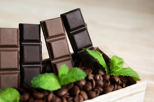 Stillleben mit Schokoladenset in Holzkiste mit Kaffeekörnern auf Holzgrund — Stockfoto