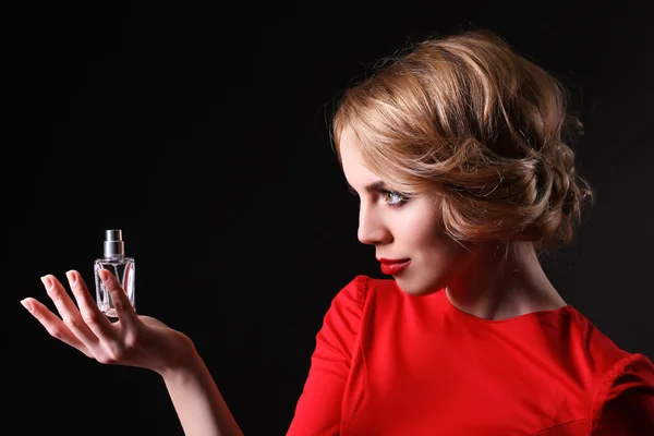 Bella giovane donna con bottiglia di profumo su sfondo nero — Foto Stock