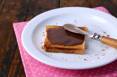 Çikolata plaka üzerinde bıçak ve peçete ahşap masa arka plan üzerinde yayılmış tost ekmeği