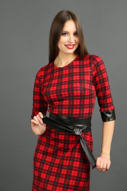 Koyu gri arka plan üzerinde kare elbiseli güzel genç kadın