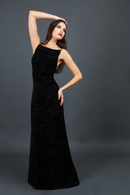 Koyu gri arka plan üzerinde uzun siyah elbiseli güzel genç kadın