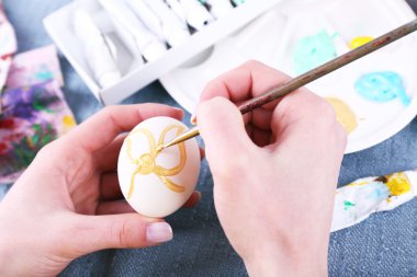 Renkli masa örtüsü arka plan üzerinde eller tarafından Paskalya yumurta boyama