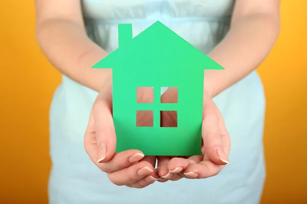 Cutout house in female hand on colorful background — Stock Photo, Image