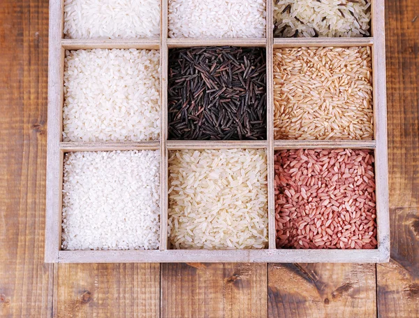 Verschillende soorten rijst in vak op houten achtergrond — Stockfoto