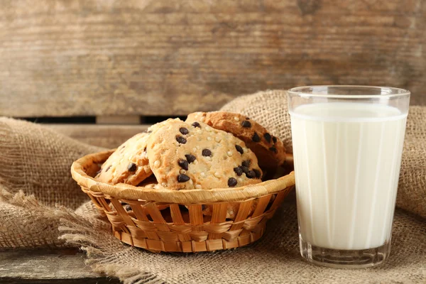 Smaczne ciastka i szklankę mleka na rustykalne drewniane tła — Zdjęcie stockowe