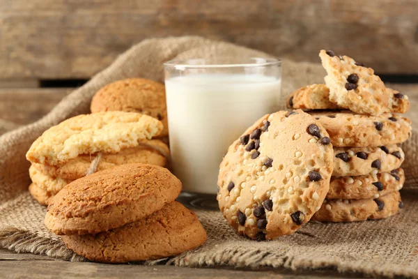 Gustosi biscotti e bicchiere di latte su fondo rustico in legno — Foto Stock