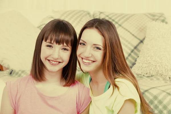 Dwie dziewczyny uśmiechający się na tło wnętrze domu — Zdjęcie stockowe