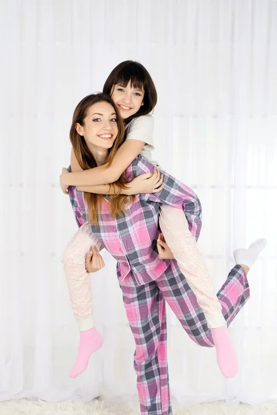 Twee meisjes in pyjama's op lichte achtergrond — Stockfoto