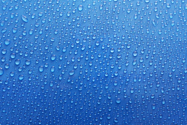 Water drops on glass on blue background — Stock Photo, Image