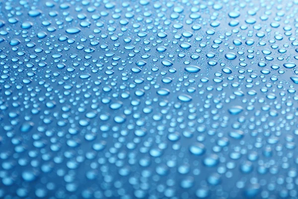 Vatten droppar på glas på blå bakgrund — Stockfoto