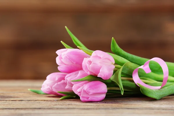 Krásné růžové tulipány s dekorativní srdce na dřevěné pozadí — Stock fotografie