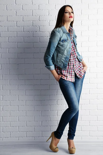Pretty girl dressed in casual style posing on white brick wall background — Stock Photo, Image