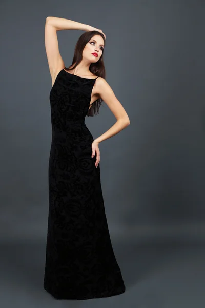 Mulher bonita em vestido preto longo no fundo cinza escuro — Fotografia de Stock