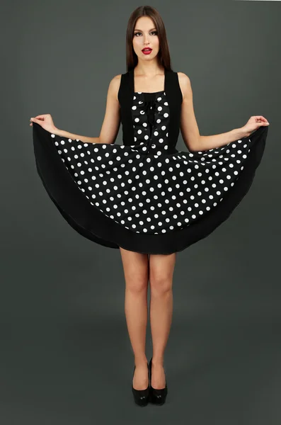 Beautiful young woman in dots dress on dark gray background — Stock Photo, Image