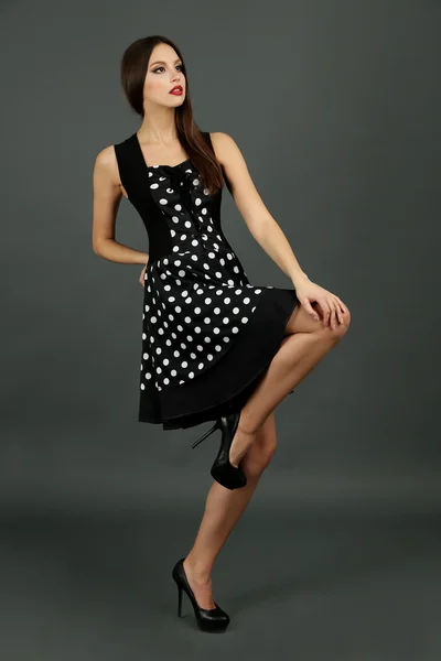 Beautiful young woman in dots dress on dark gray background — Stock Photo, Image