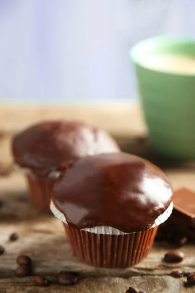 Νόστιμο σπιτικό muffins σοκολάτας και φλιτζάνι καφέ στο ξύλινο τραπέζι, επάνω ελαφρύς υπόβαθρο — Φωτογραφία Αρχείου