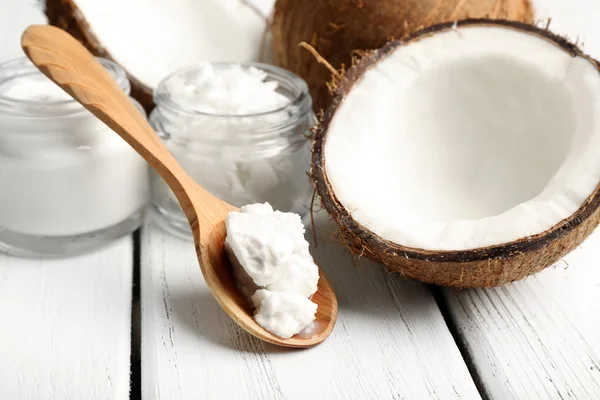 Cocco con vasetti di olio di cocco e crema cosmetica su fondo di legno — Foto Stock